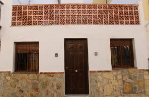 a house with two doors and a stone wall at San Amador in Martos