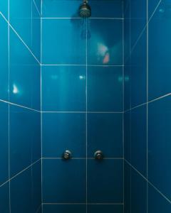 een blauwe betegelde douche met een douchekop bij Wild Monkey Hostel in Cuenca