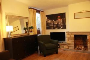 3 bedroom flat in Maida Vale في لندن: غرفة معيشة فيها موقد وكرسي وتلفزيون