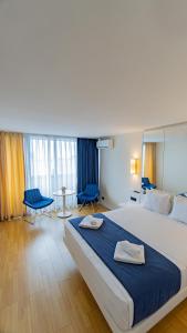 a hotel room with a large bed and blue chairs at Smart Aparthotel Orbi City in Batumi