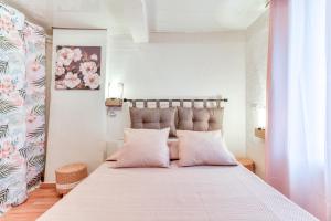 a bedroom with a large bed with pink pillows at Le petit rubis d'Ouveillan in Ouveillan