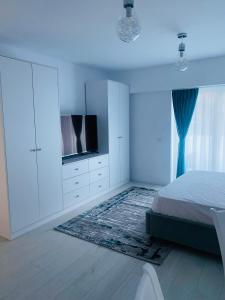 um quarto branco com uma cama e uma televisão de ecrã plano em Luxury Prince em Câmpulung Moldovenesc
