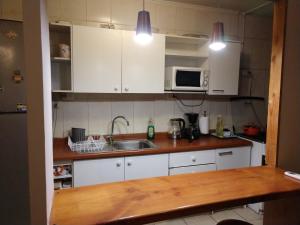 cocina con armarios blancos, fregadero y microondas en Departamento Los Andes, en Los Andes