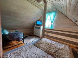 a bedroom with a bed in a wooden cabin at Siedlisko Swojskie Klimaty in Trześcianka