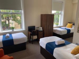 a hotel room with two beds and a desk with a chair at The New Brighton Hotel in New Brighton