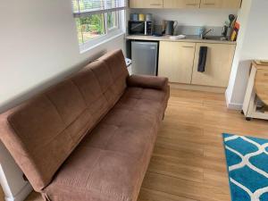 um sofá castanho numa sala de estar com uma cozinha em Old Ferry View em Bristol