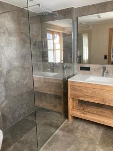 a bathroom with a shower and a sink and a mirror at Lodge14 in Kirchberg in Tirol
