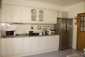 a kitchen with white cabinets and a stainless steel refrigerator at Ivone Madeira Guest House in Funchal