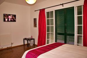 a bedroom with a bed with red curtains and a window at Ivone Madeira Guest House in Funchal