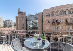 a table with two glasses of wine on a balcony at Paamonim Studios in Jerusalem