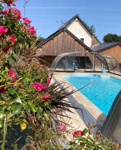 a swimming pool next to a house with pink flowers at L'Escale Normande in Saint-Jean-des-Champs