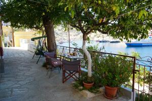 a table and chairs under a tree next to the water at Pitini Sevasti house in Symi