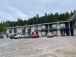 un edificio con coches estacionados en un estacionamiento en Motel du rosier, en Baie-Comeau