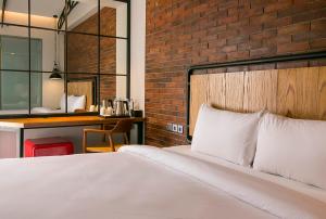 een slaapkamer met een bed en een bakstenen muur bij Posto Dormire Hotel in Jakarta