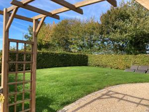 a garden with a wooden pergola and a lawn at L'Escale Normande in Saint-Jean-des-Champs