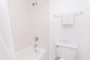 La salle de bains blanche est pourvue d'une douche et de toilettes. dans l'établissement Girasole Apartments, à Miami Beach