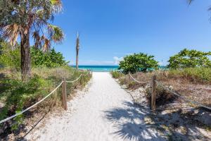 un camino a la playa con palmeras y el océano en Girasole Apartments, en Miami Beach