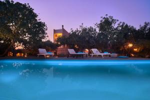 una piscina con sillas, una mesa y un edificio en Unique Venetian Style Villa "Leniko" in Crete, en Atsipopoulo
