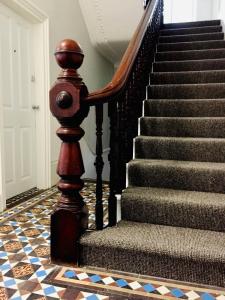 a stairway with a wooden rail and a staircase withchrome tiles at Deluxe Huge Detached House with Parking, sleeps up to 30 people, 2m from Liverpool City Centre in Liverpool