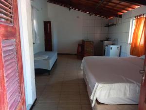 a bedroom with two beds and a kitchen with a refrigerator at Paracuru Olaonda wavehostel in Paracuru