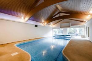 a swimming pool in a large room with a ceiling at Coach house in Woking