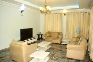 Il comprend un salon avec des canapés et une télévision à écran plat. dans l'établissement Opal Ville Bamboo Suite, 2-bedroom in a serene area, à Abuja