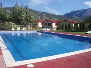 a large blue swimming pool with mountains in the background at Bungalowpark Isábena in La Puebla de Roda