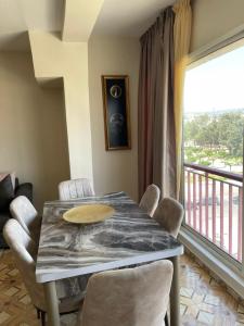 een eetkamer met een tafel en stoelen en een balkon bij Cosy appartement au super centre ville avec vue partielle sur le parc in Agadir