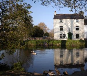 a house on the water with ducks in front of it at Fitzwarine House Whittington in Whittington