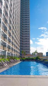 a large building with a swimming pool in front of a building at StayInMyCondo - 8th Condo in Pasay near NAIA Airport, MOA Pasay in Manila
