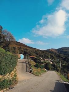 un camino vacío en una colina con un pequeño pueblo en La Nozal - La Vallicuerra Casas Rurales en Mieres