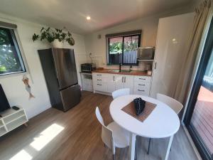 a kitchen with a white table and a refrigerator at Red Beach Garden Cottage in Red Beach
