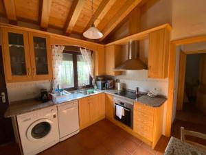a kitchen with wooden cabinets and a washer and dryer at El huerto de Lino in Candeleda