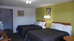 Habitación de hotel con 2 camas y mesa en Robyn's Motel en Peterborough