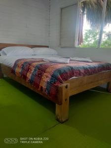 a bed with a wooden frame on a green floor at Cabaña en Playa Blanca, Barú In house beach in Baru