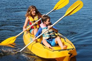 dos niños en un kayak amarillo en el agua en Red Beach Garden Cottage, en Red Beach
