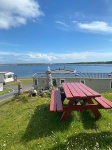 a picnic table sitting on the grass near the water at Port Haverigg Holiday Village in Millom