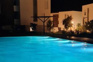 - une grande piscine bleue la nuit dans l'établissement Taghazoutbay Résidence Tamourrit Appart, à Taghazout