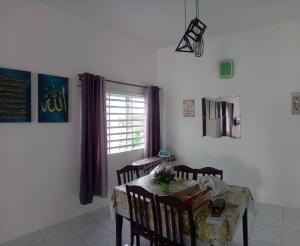 a dining room with a table and chairs and a window at Homestay D'Mama Īfor mūslimĪ in Tanjung Malim