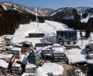 uma pequena cidade coberta de neve com uma pista de esqui em 野沢温泉ロッヂ em Nozawa Onsen