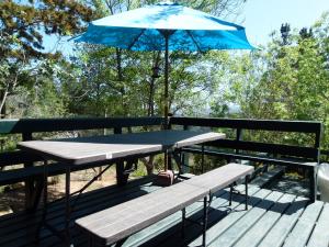 a picnic table with a blue umbrella on a deck at Casa Tunquén in Tunquen