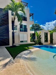 a house with a palm tree and a swimming pool at Villa Tendenza Condo in Playa del Carmen