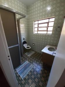 La salle de bains est pourvue de toilettes et d'un lavabo. dans l'établissement Casa Praia Grande - Solemar, à Praia Grande