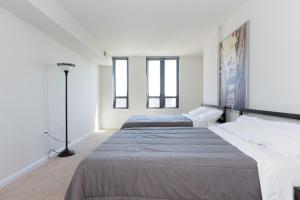 two beds in a white room with windows at Nice 2BR Pentagon City Apartment in Arlington