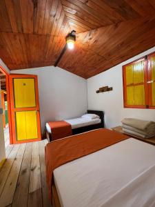 a bedroom with two beds and a wooden ceiling at Hospedaje Campestre El Rancho de Jero in Jardin