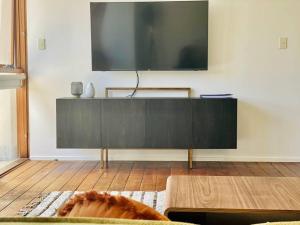 a living room with a large television on a wall at Poolside Apartment In Central Byron in Byron Bay