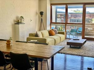 a living room with a couch and a table at Poolside Apartment In Central Byron in Byron Bay