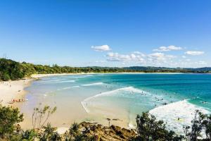 a beach with a bunch of people in the water at Poolside Apartment In Central Byron in Byron Bay