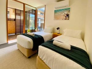 1 dormitorio con 2 camas y ventana en Poolside Apartment In Central Byron, en Byron Bay