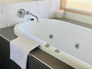 a bathroom with a bath tub with a towel at Poolside Apartment In Central Byron in Byron Bay +24 photos